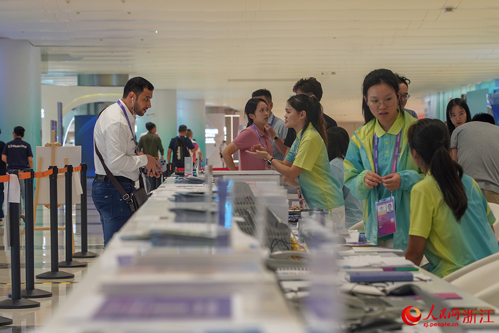 杭州亞運會主媒體中心里，志愿者為記者提供咨詢服務。人民網 章勇濤攝