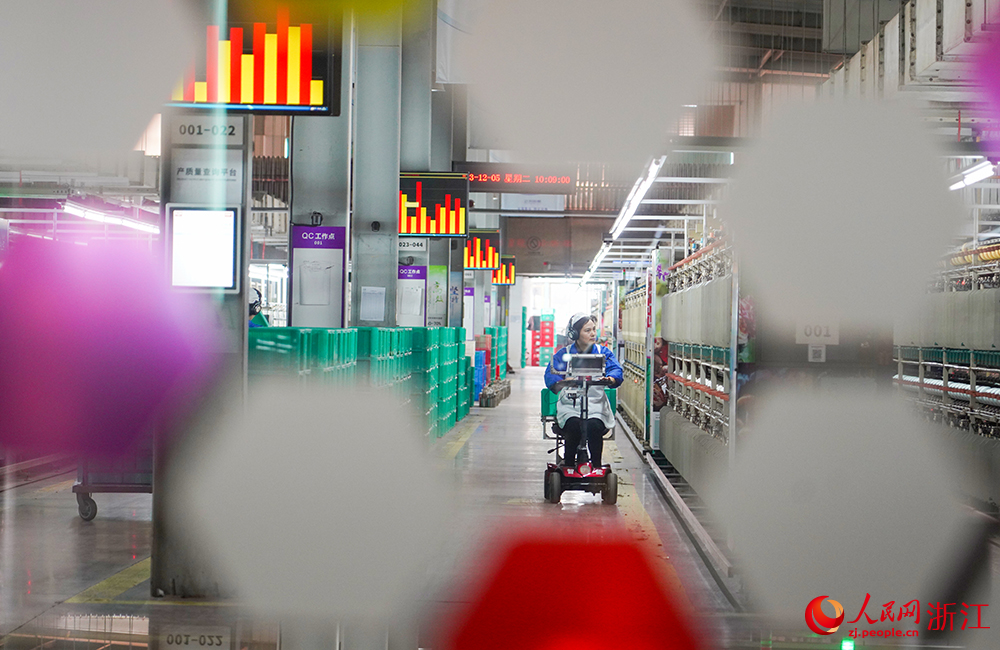 浙江省紹興市新昌縣達利絲綢智能工廠內一派繁忙，工人在生產線上趕制訂單。人民網 章勇濤攝