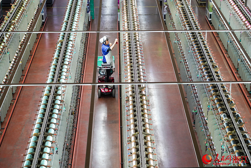 浙江省紹興市新昌縣達利絲綢智能工廠內一派繁忙，工人在生產線上趕制訂單。人民網 章勇濤攝