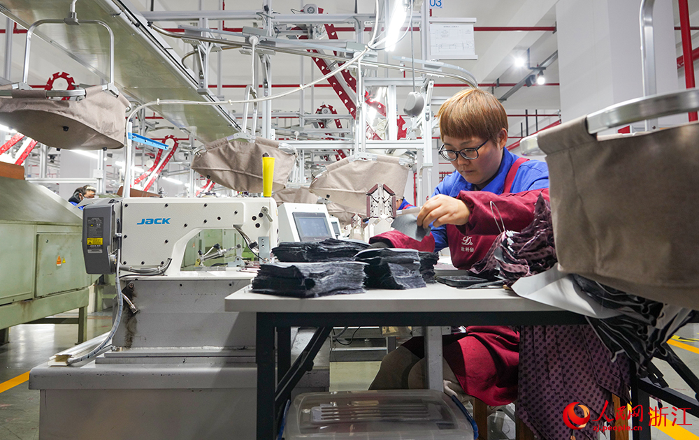 浙江省紹興市新昌縣達利絲綢智能工廠內一派繁忙，工人在生產線上趕制訂單。人民網 章勇濤攝