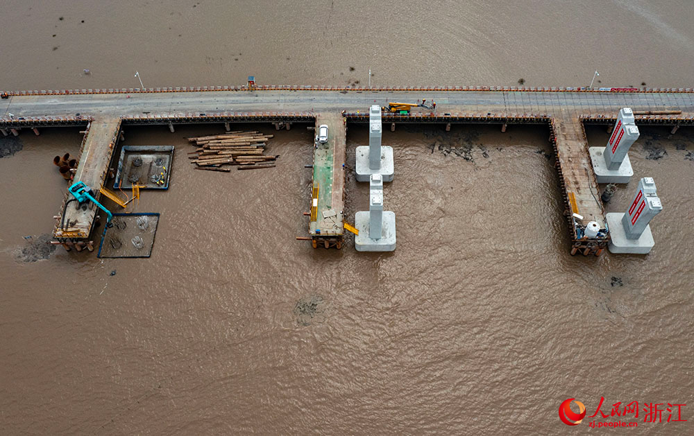 3月12日，在寧波市鎮海區灰鱉洋南岸灘涂之上，工人在棧橋搭建起的海上施工通道上有序施工。人民網 章勇濤攝