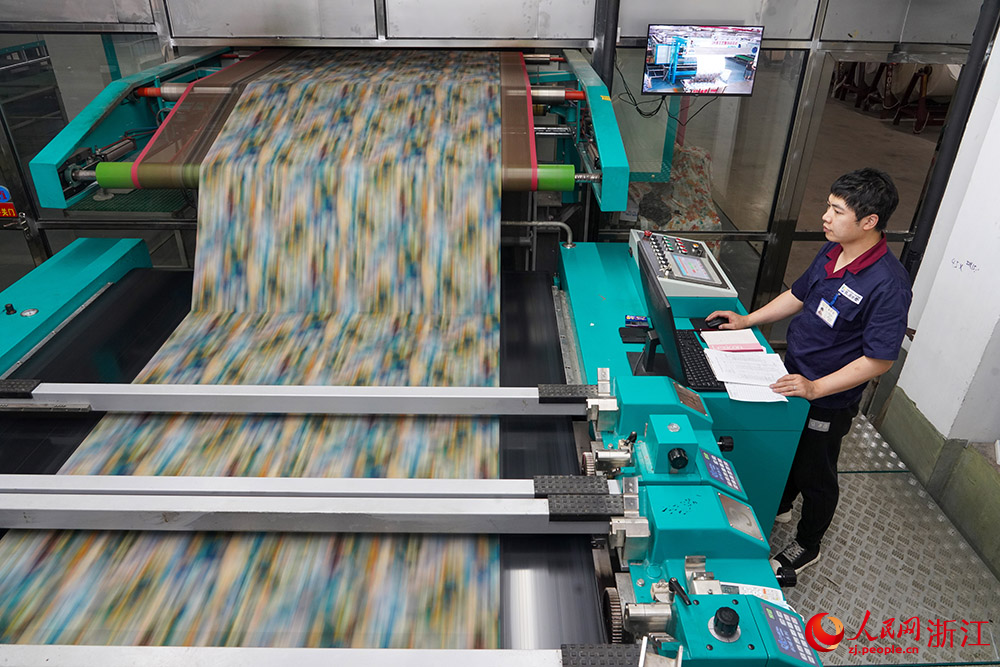 在浙江省紹興市柯橋區的印染企業，工人在數碼印花產線上趕制訂單。人民網 章勇濤攝