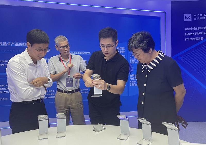 裴顥(右二)向到訪嘉賓介紹公司的高通量單細胞測序產品。受訪者供圖