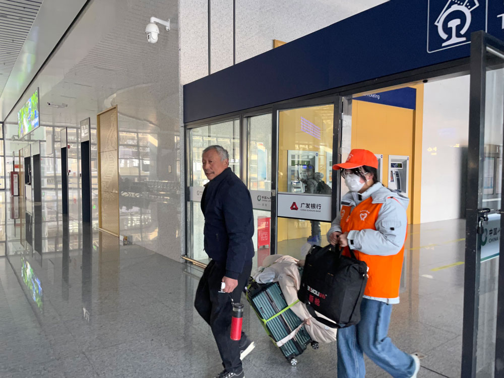 在臨海站，志愿者幫旅客提行李。李洋攝