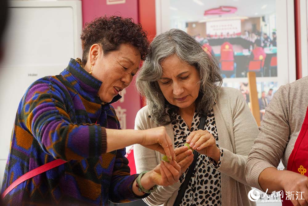 浙江省義烏市江東街道雞鳴山社區中外居民共同制作清明果。人民網 章勇濤攝