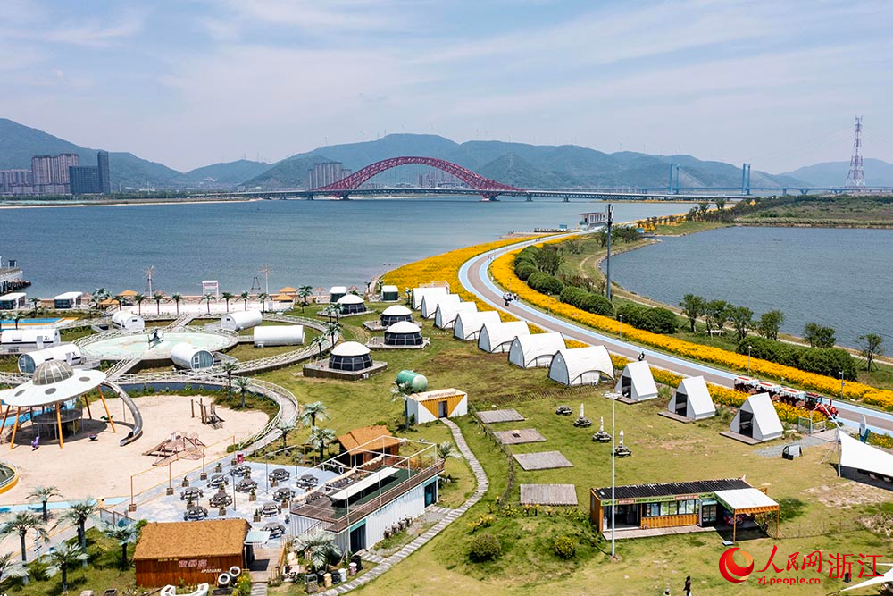 寧波市北侖區梅山灣梅山紅橋下，一片花海景色吸引了眾多游客前來觀賞。人民網 章勇濤攝