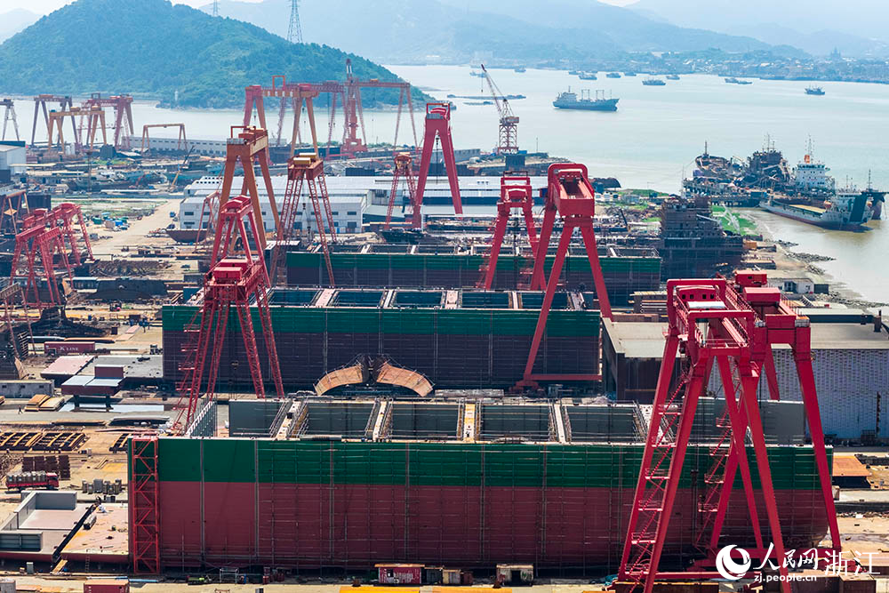 在浙江省寧波市象山縣石浦鎮打鼓峙臨港裝備制造基地，巨大的龍門吊緩緩移動，吊臂車在船體間穿梭自如，呈現一派熱火朝天的生產景象。人民網 章勇濤攝