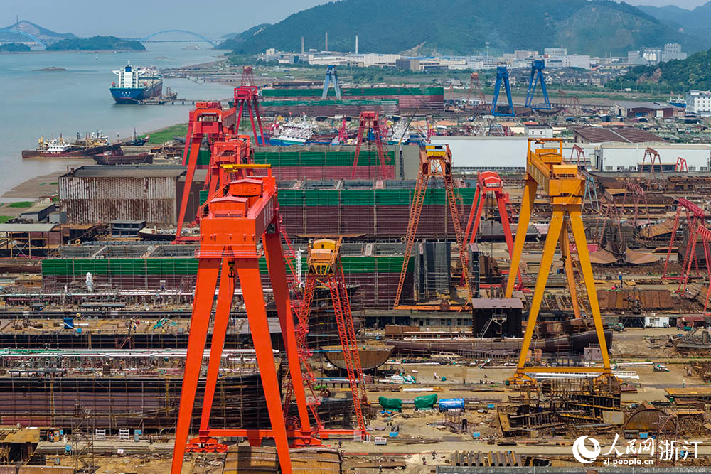在浙江省寧波市象山縣石浦鎮打鼓峙臨港裝備制造基地，巨大的龍門吊緩緩移動，吊臂車在船體間穿梭自如，呈現一派熱火朝天的生產景象。人民網 章勇濤攝