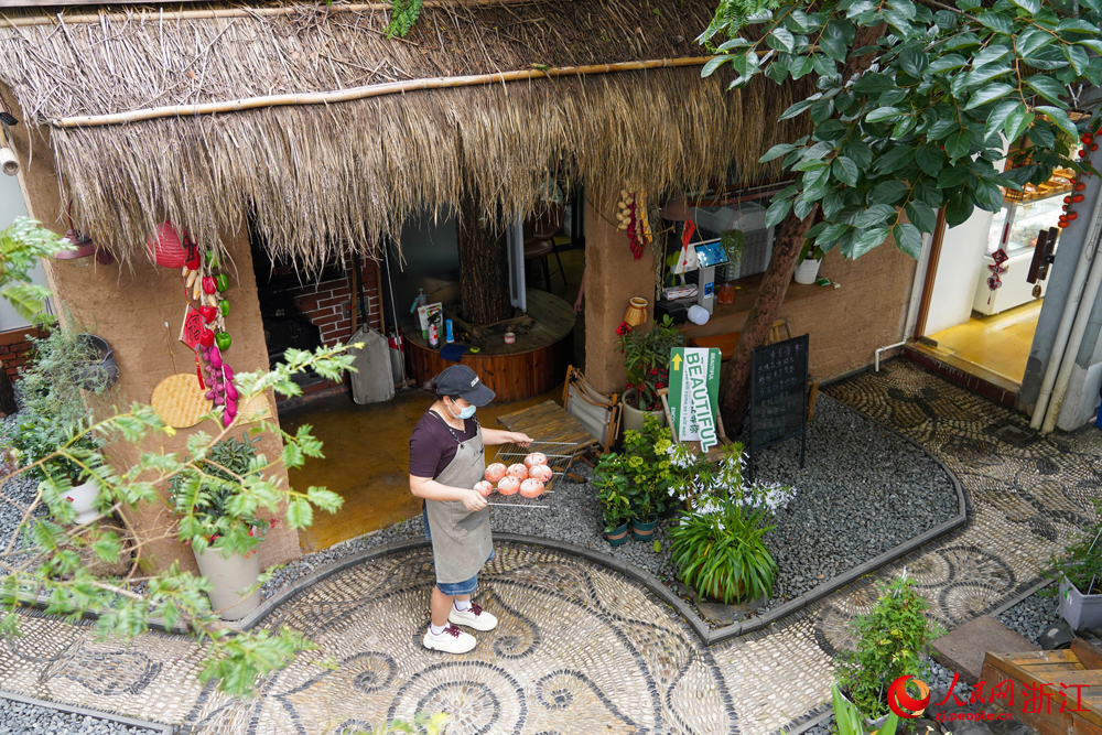 6月25日，寧波市寧?？h躍龍街道溪南劉村，工作人員在搬運剛出爐的面包。該村一處由自家老房子改建而成的庭院式面包房，已成為當地典型的小院經濟代表。人民網 章勇濤攝