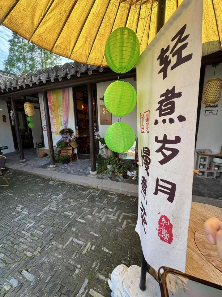 院內的油紙傘下，“輕煮歲月慢煮茶”七個字好似節拍器一般放慢了來客的步伐。人民網記者 龔莎攝