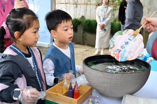 活動現場，“廉潔文化創意集市”吸引眾多游客駐足體驗，圖為小朋友在體驗漆扇藝術。余姚市紀委供圖